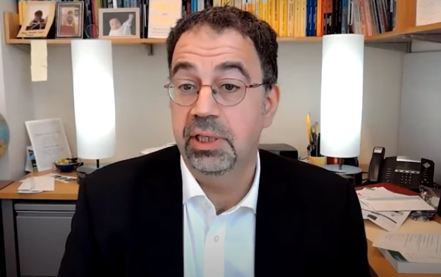 Prof Daron Acemoglu talking in his office via videoconference